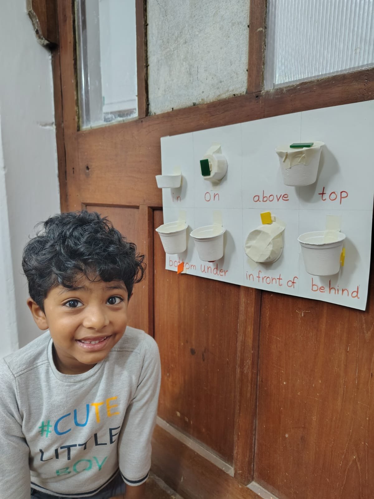 A smiling First Step child beside the position words board at bms