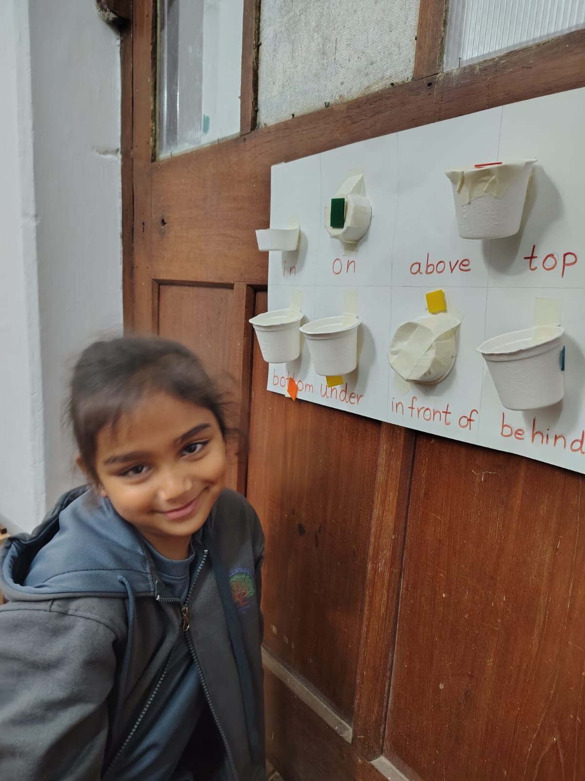 A First Step child placing an object on the position words board
