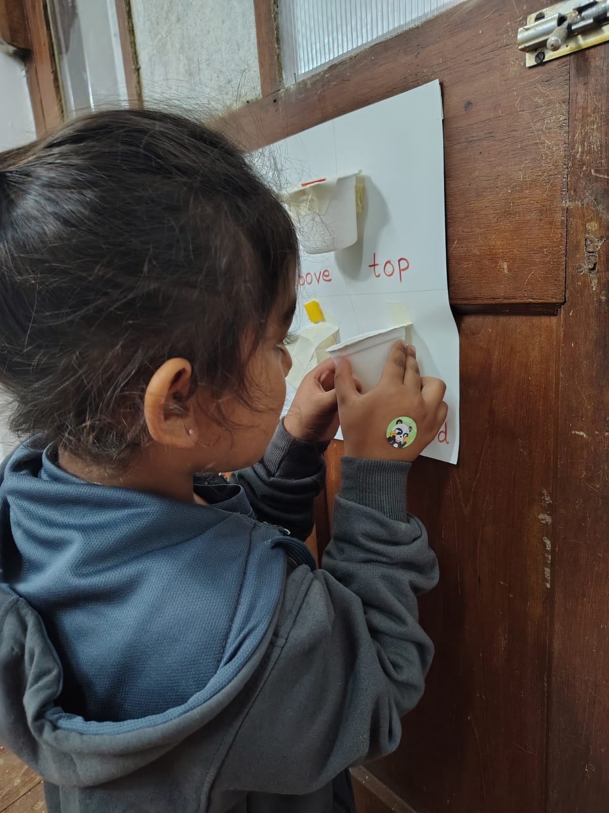 A First Step child placing an object on the position words board