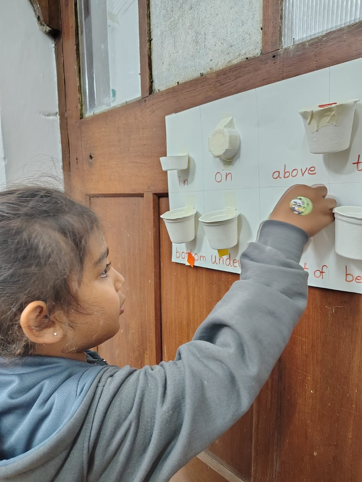 A First Step child placing an object on the position words board