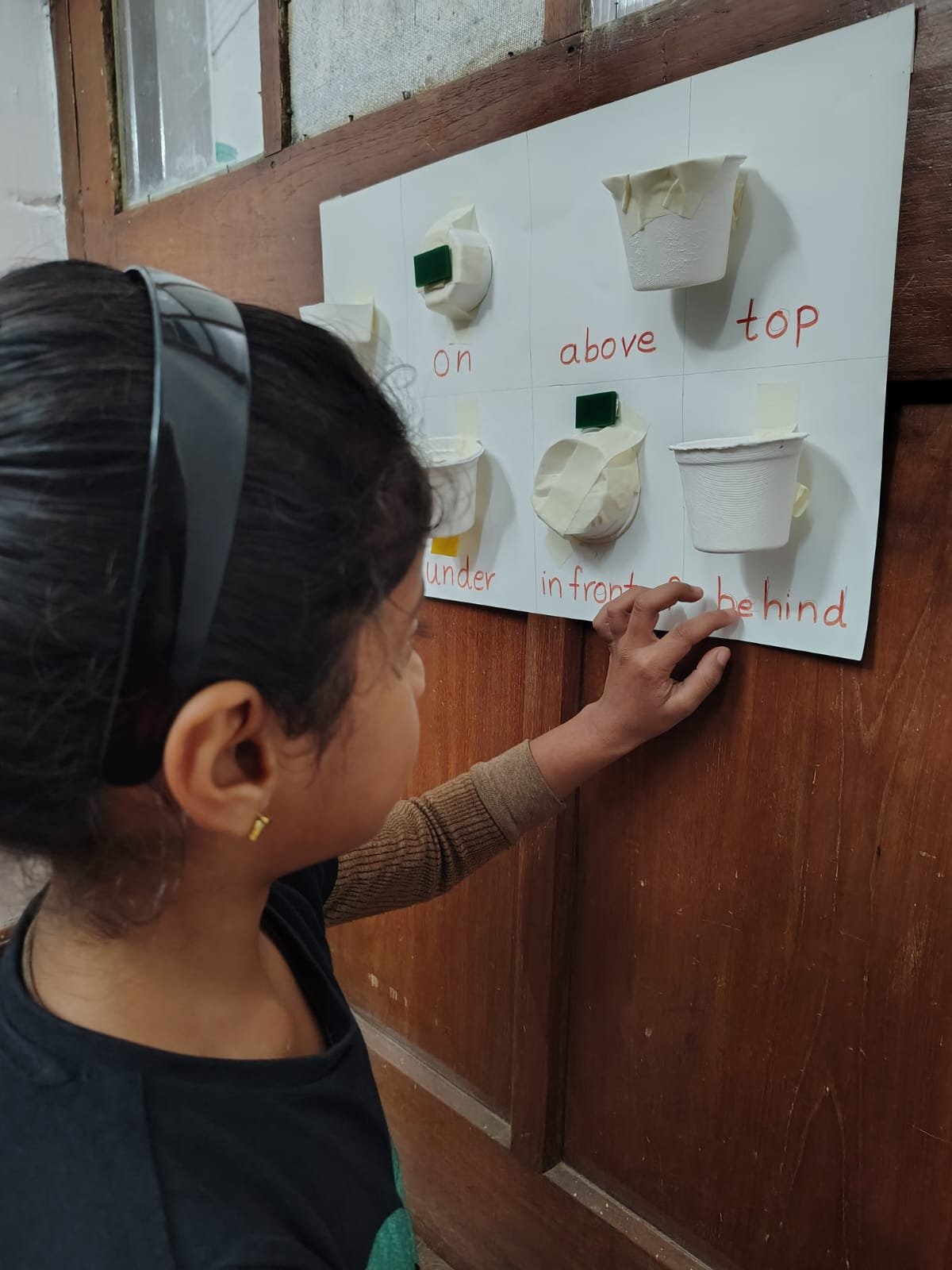 A First Step child placing an object on the position words board