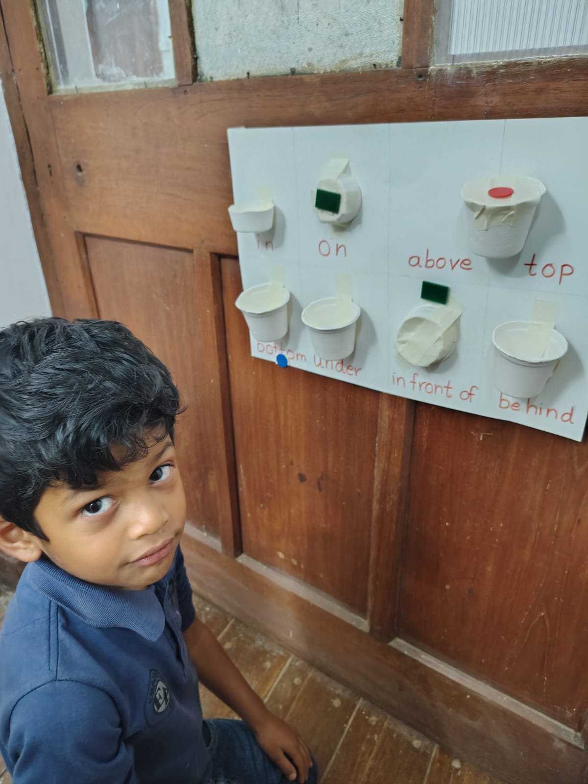 A First Step child placing an object on the position words board