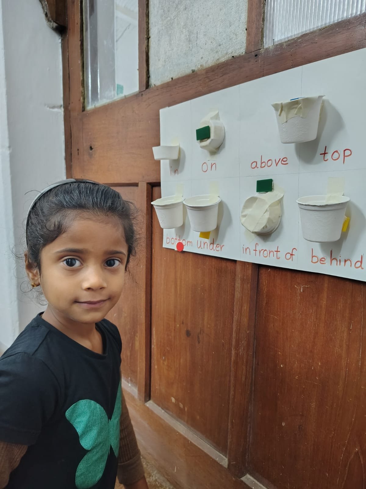 A First Step child placing an object on the position words board