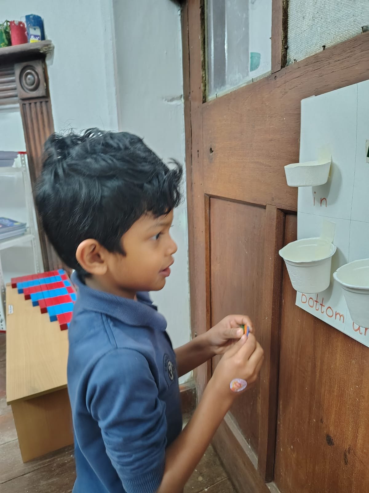 A First Step child placing an object on the position words board