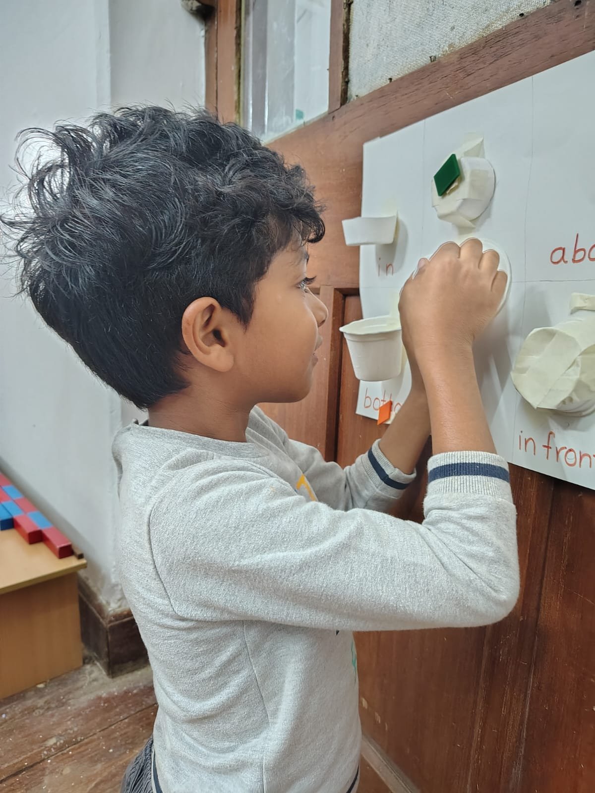 A First Step child placing an object on the position words board