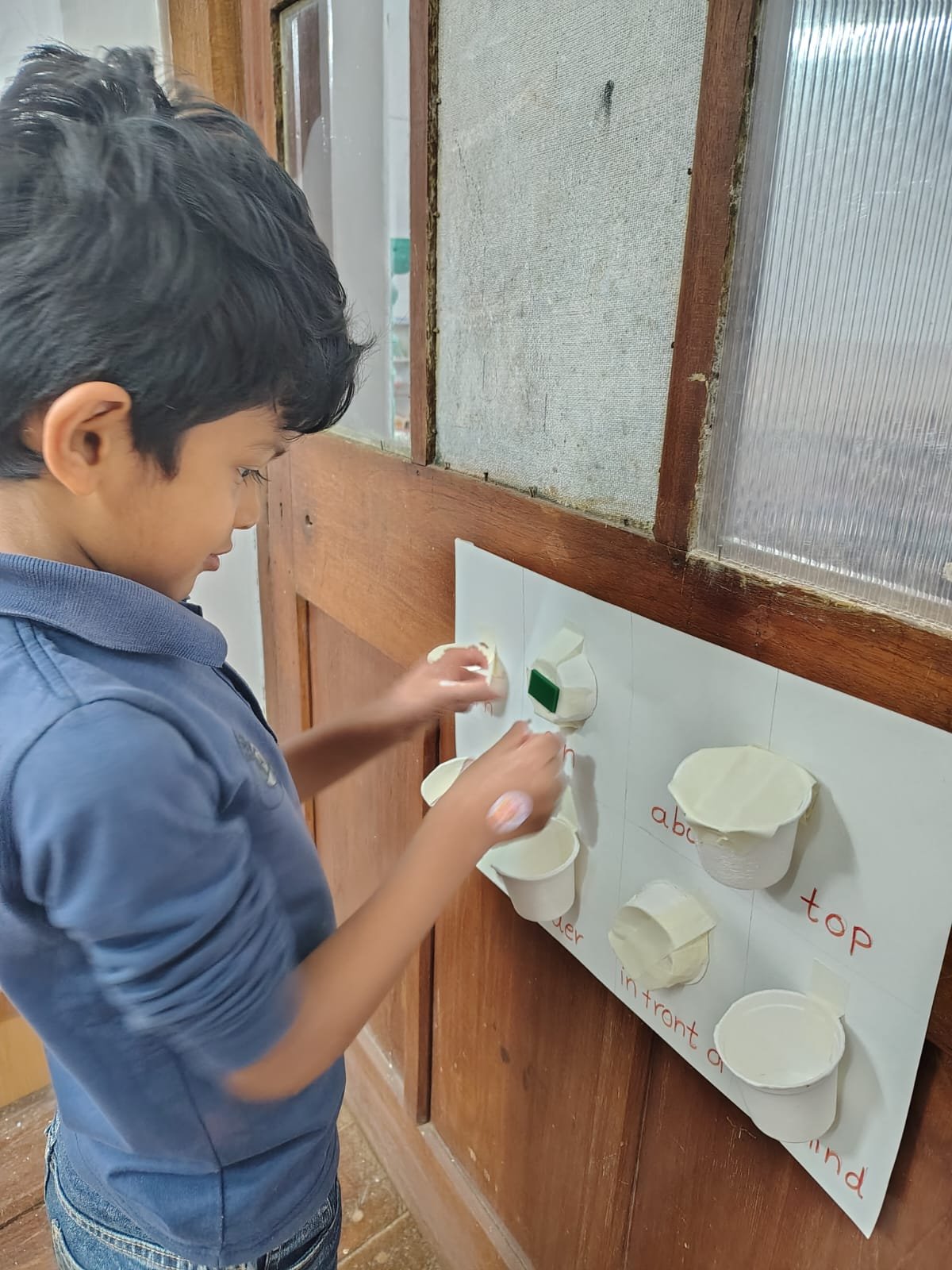 A First Step child placing an object on the position words board