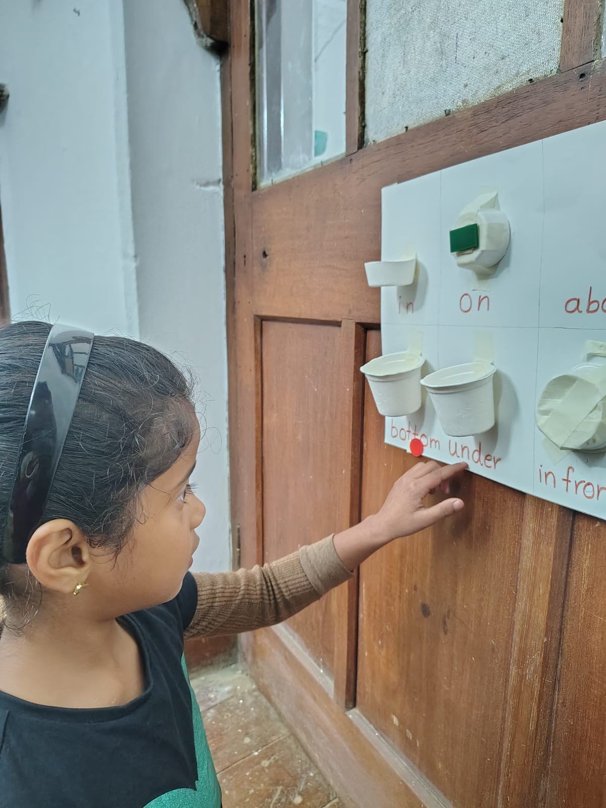 A First Step child placing an object on the position words board