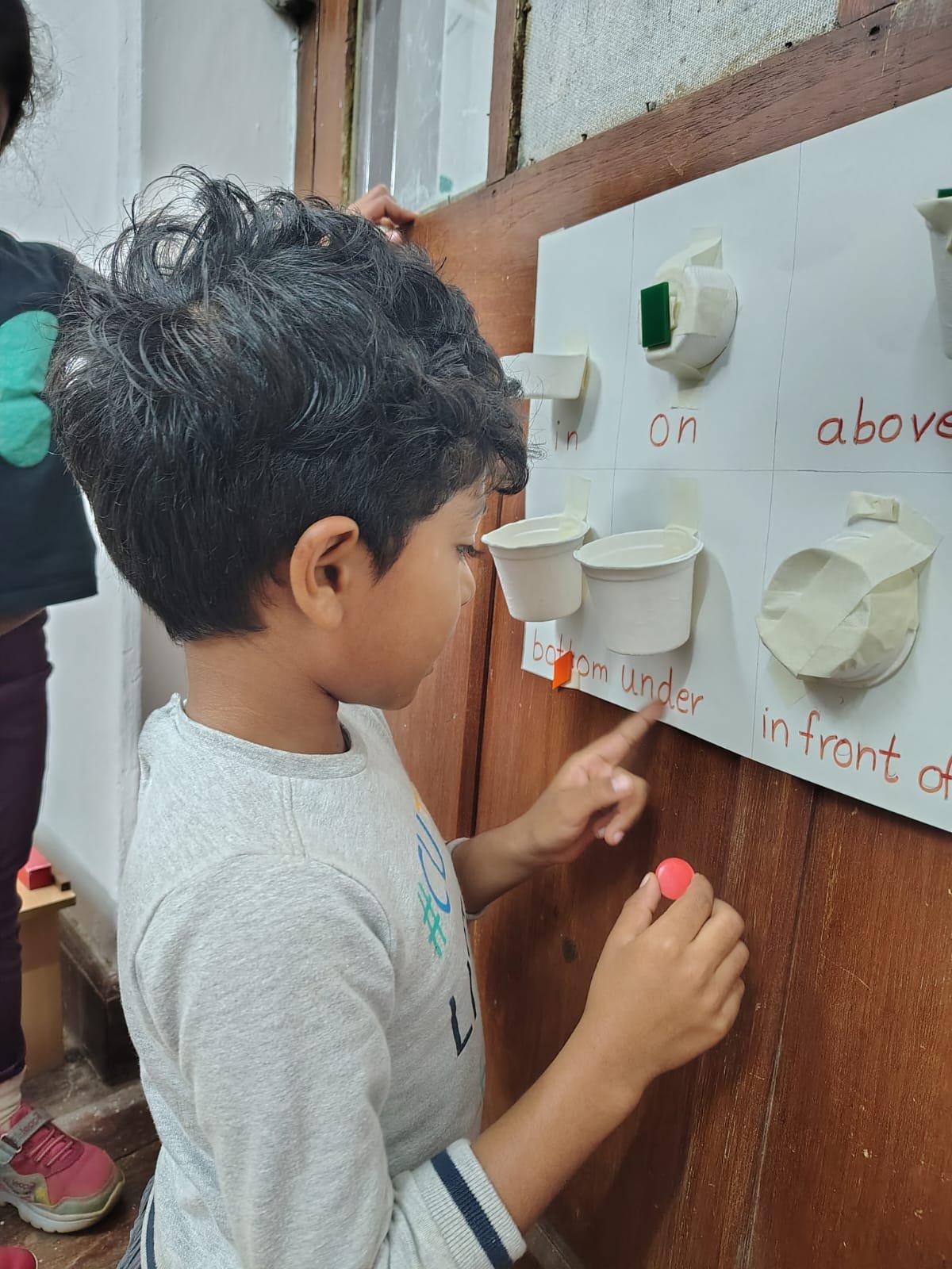 A First Step child placing an object on the position words board