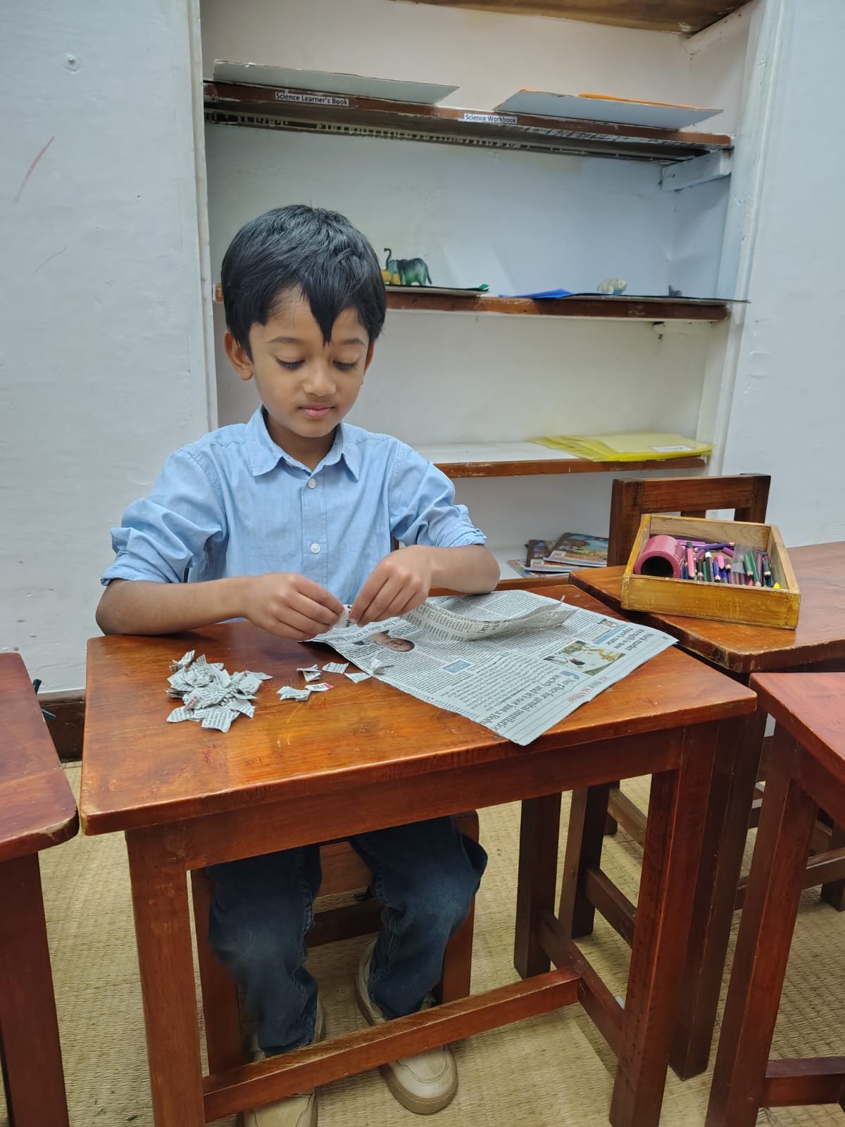 A Grade 1 child tearing old newspaper for handmade paper