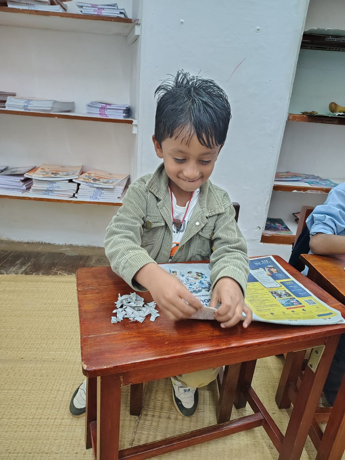 A Grade 1 child tearing old newspaper for handmade paper