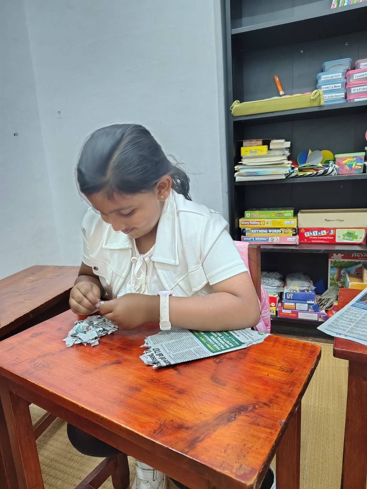 A Grade 1 child tearing old newspaper for handmade paper