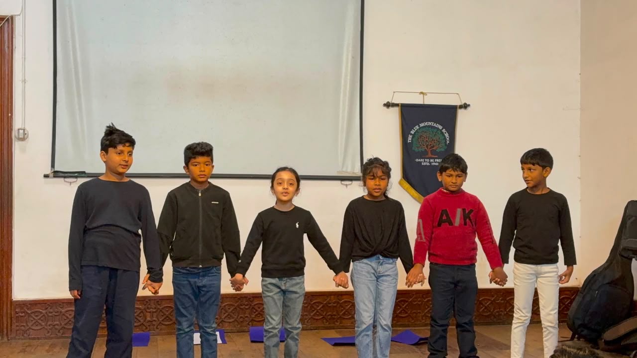 Grade 3 students holding hands on stage during their Do-Re-Mi reading assembly