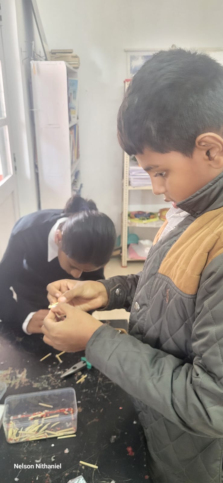A student joining matchsticks by hand