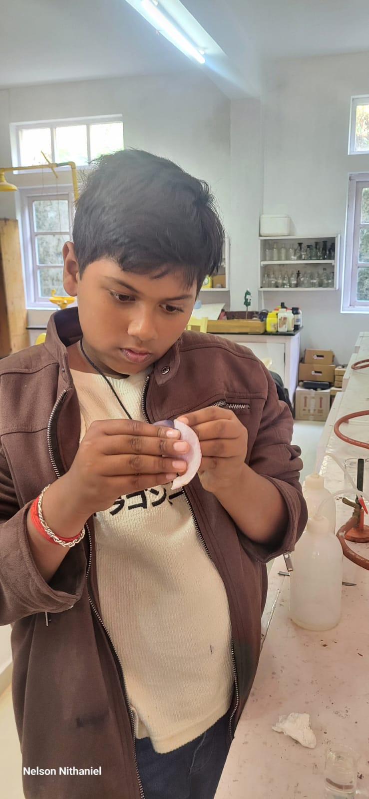 A student carefully holding a thin, translucent piece of onion peel