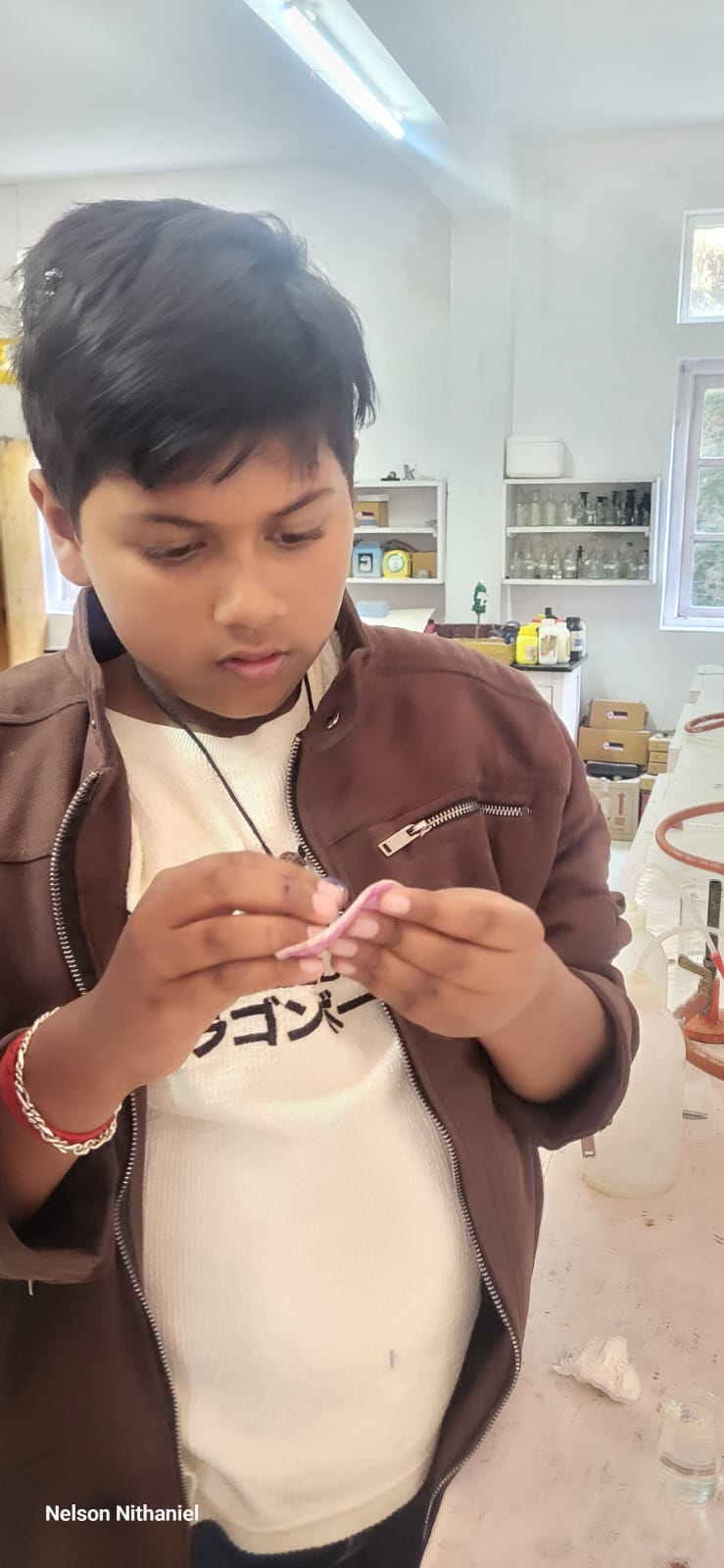 A student examining a piece of onion peel between his fingers