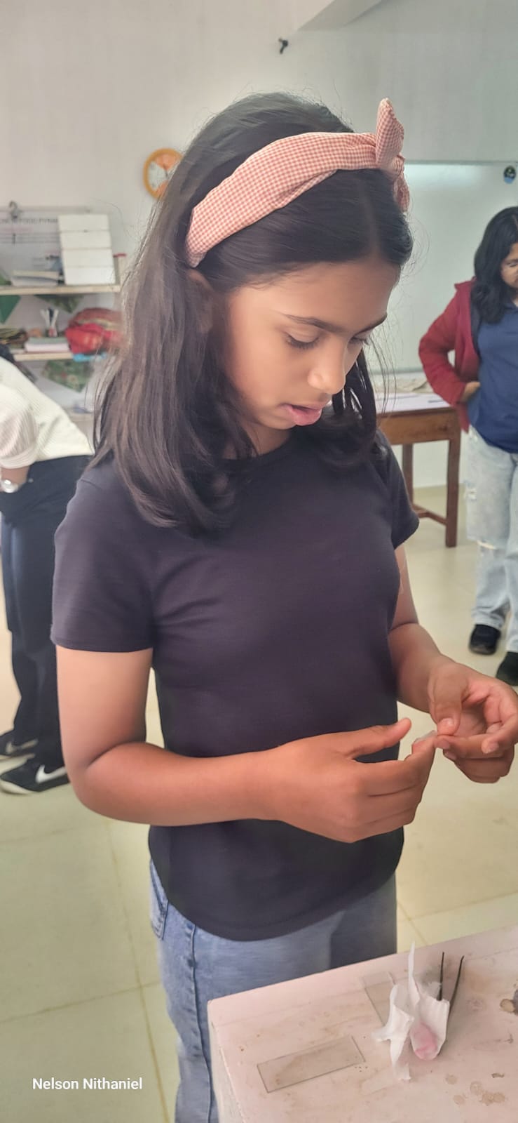 A student holding a thin strip of onion peel ready for the slide