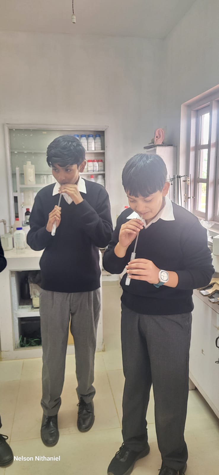 Two students blowing exhaled air into their test tubes side by side