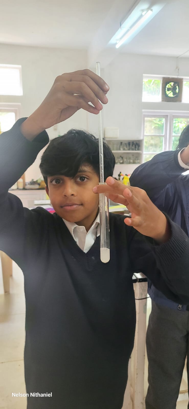 A student holding up a test tube showing lime water turned milky