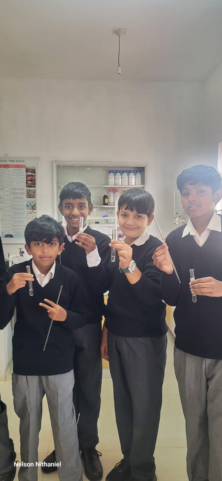 Four students holding up their test tubes of milky lime water
