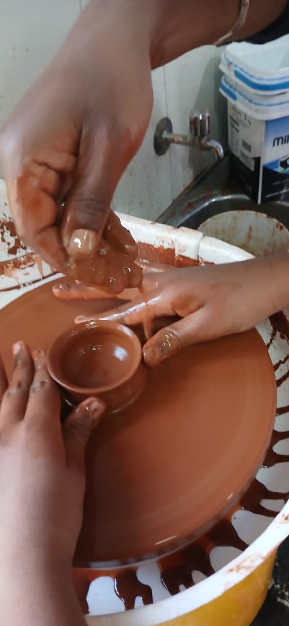 Hands shaping a small clay bowl on the potter's wheel