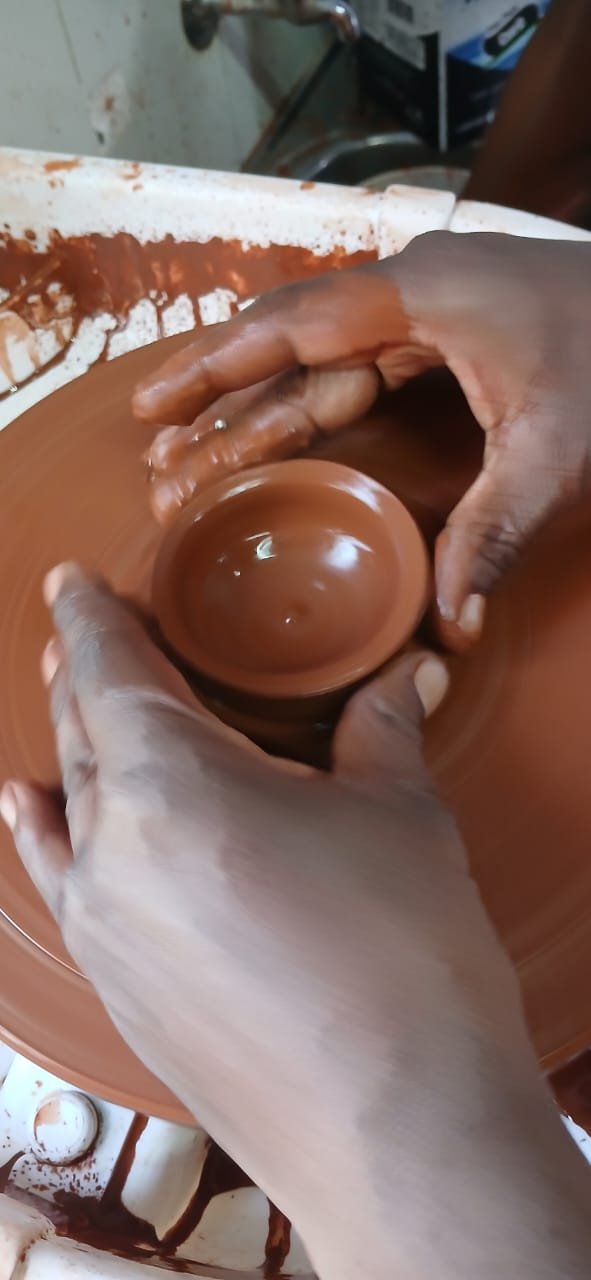 Hands forming a clay bowl on the wheel