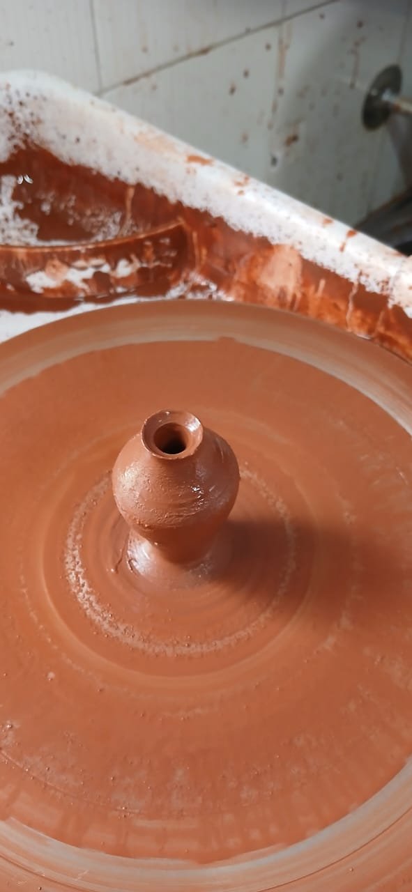 A small clay pot taking shape on the potter's wheel