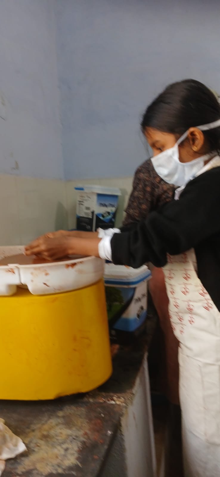 A girl in a mask working at the potter's wheel