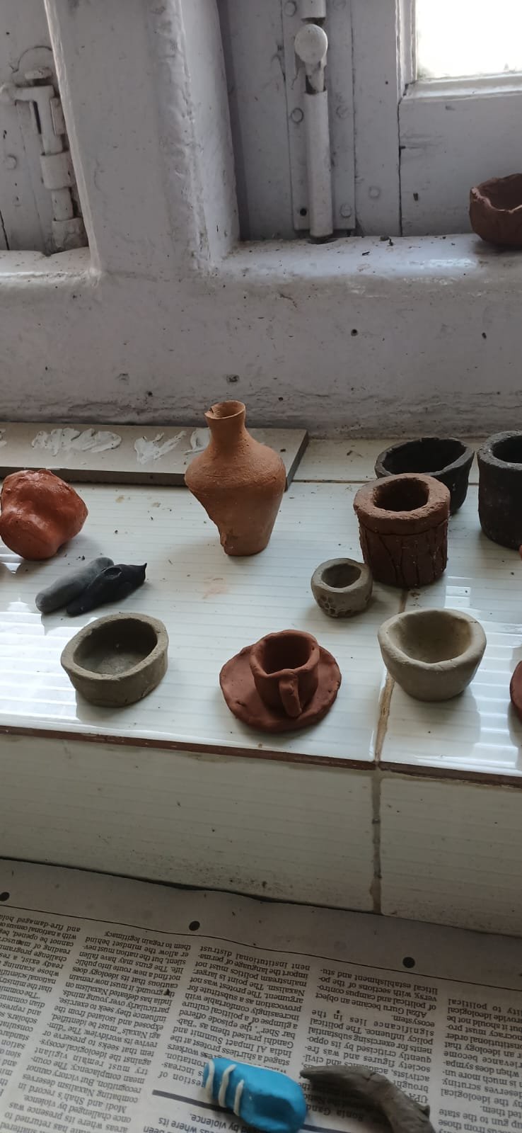 Finished clay pots and bowls drying on the windowsill