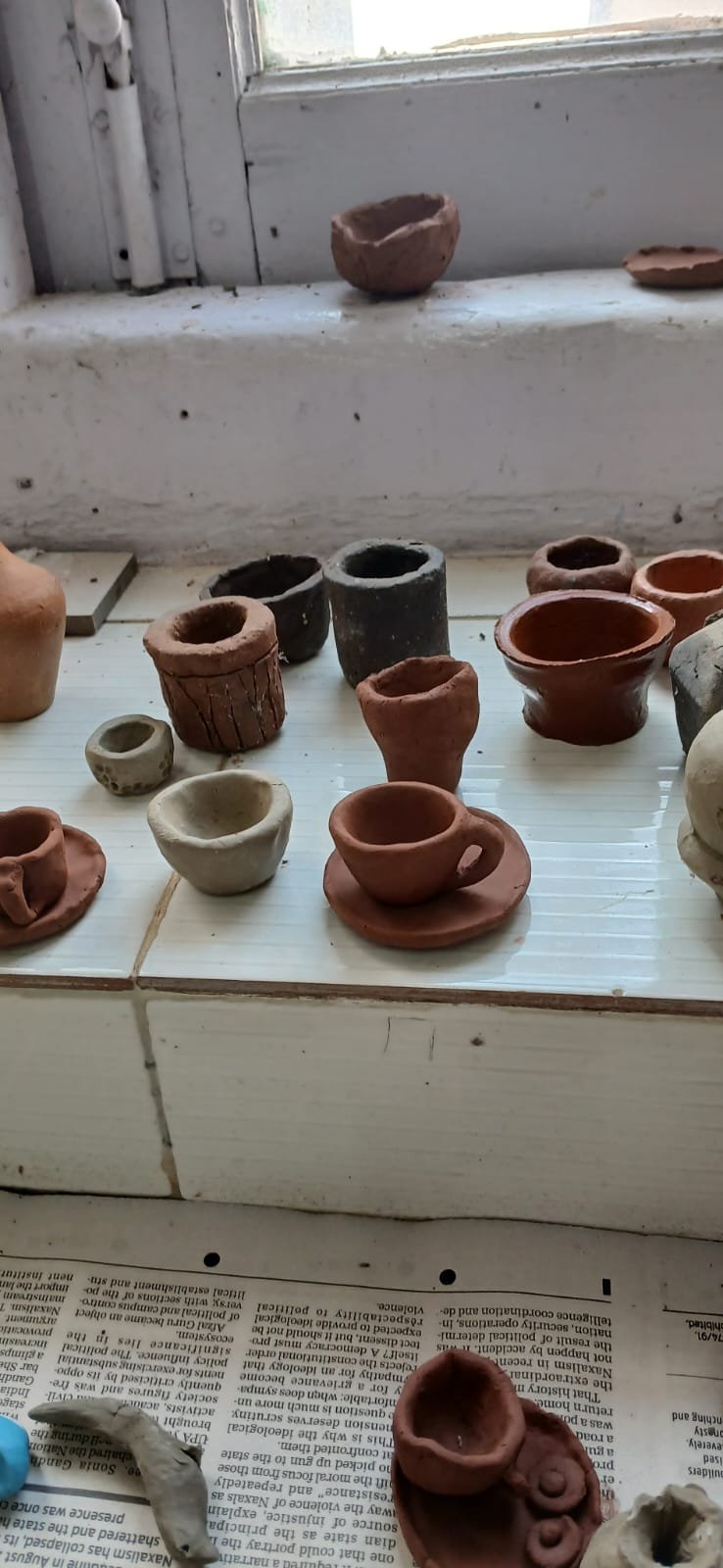 Finished clay pots and bowls drying on the windowsill