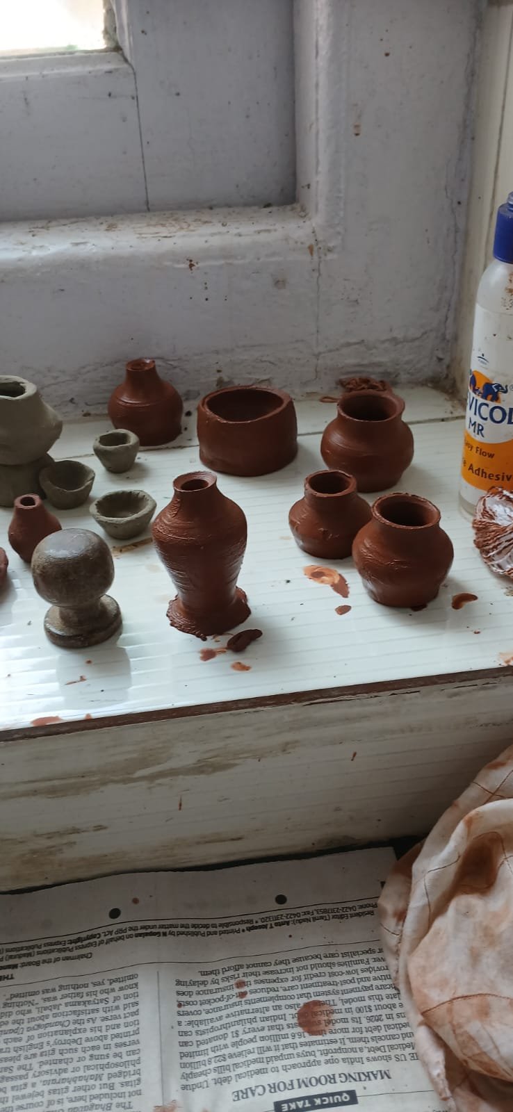 Finished clay pots and bowls drying on the windowsill