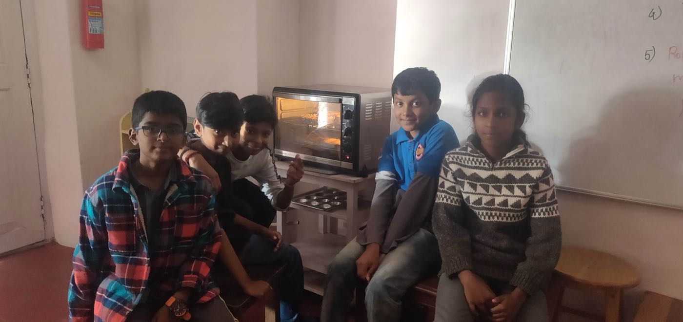 Grade 5 students with their chocolate chip cookies baking in the toaster oven at bms
