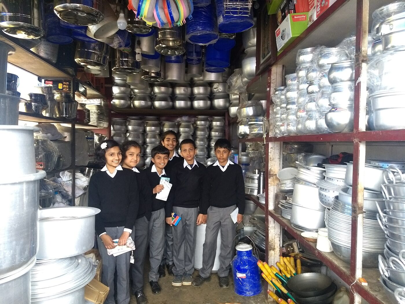 Students surrounded by aluminum vessels at Rex Stores